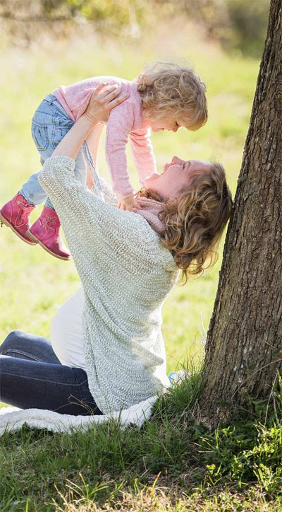 Happy woman lifting a child in the air